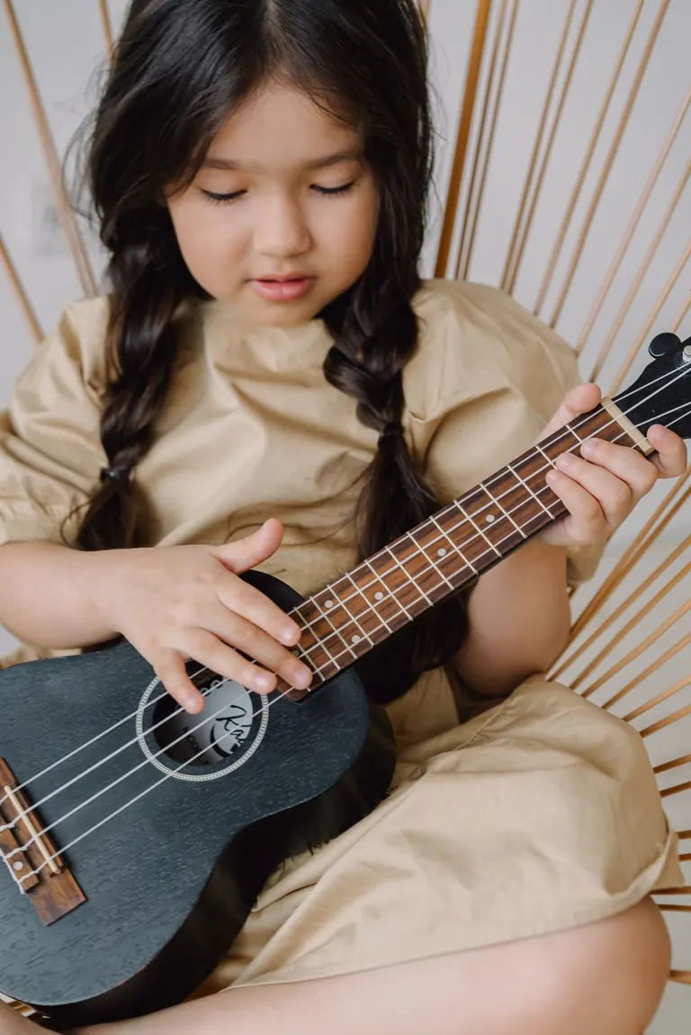Young student playing ukulele indoors